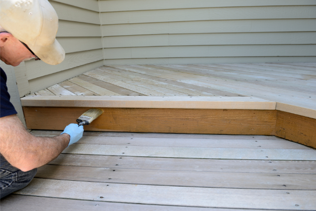 Worker Brushing on Stain of a backyard deck