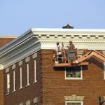 Commercial Painters on a lift painting the top of a building