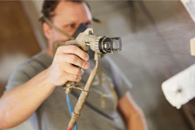 Worker with paint and stain sprayer